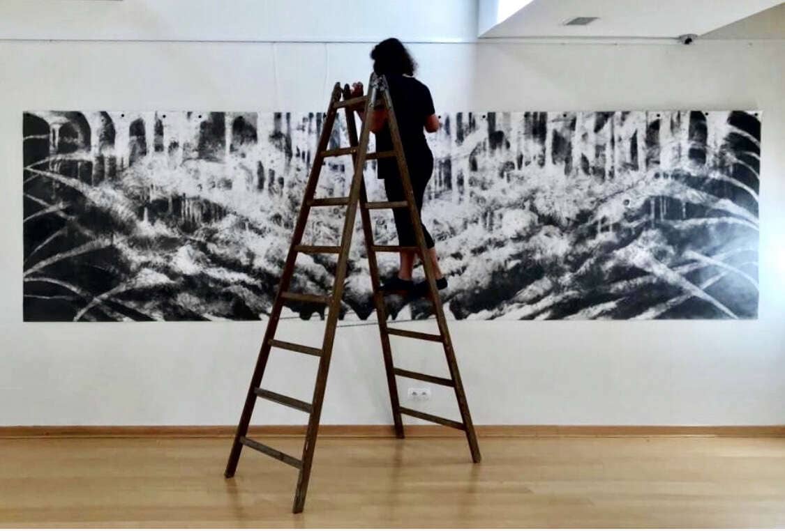 Stunning black and white mural being installed by an artist on a wooden wall at UVU Review campus. Creative mural art enhances visual appeal for university art exhibitions.