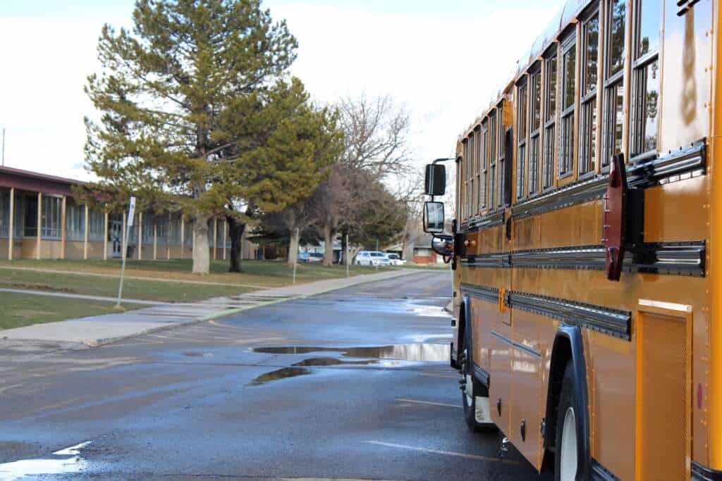 School bus parked outside a university campus, UVU Review, Utah Valley University, educational institution, campus life, transportation, student transportation, university grounds, school transportation, academic environment, college campus, vehicle on campus, university vehicle, student life, campus infrastructure.