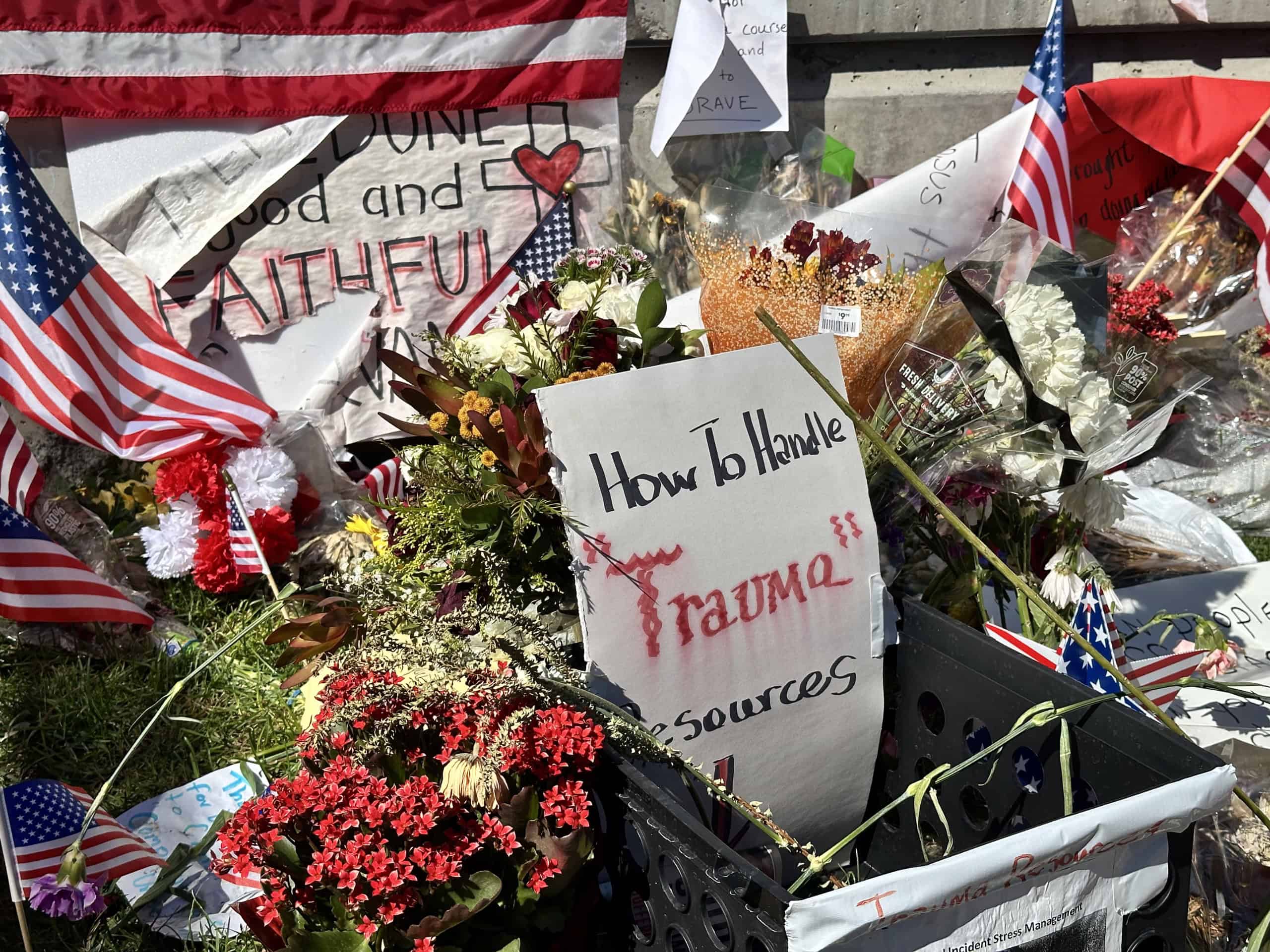 A sign reads "How to handle trauma: resources" alongside flowers.